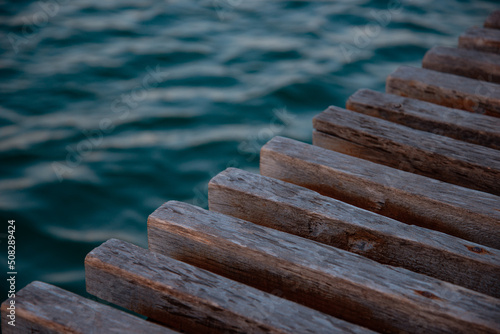 A wooden pier made of beams close-up extending into the ocean.