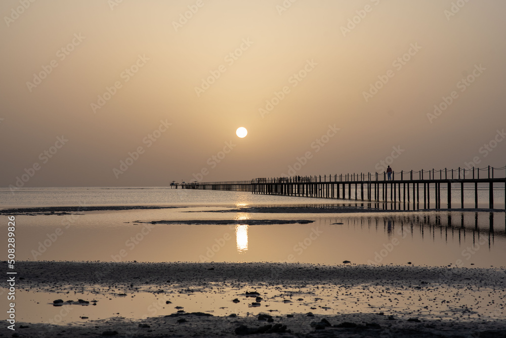 Fototapeta premium Wooden dock at the lake, sunrise at the sea