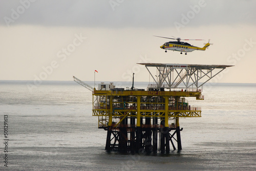 A helicopter on top of a offshore oil-platform transporting roughnecks to nearby rigs photo