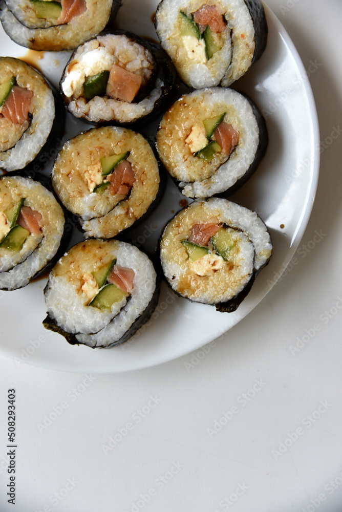 Rice rolls with salmon and cheese on a white plate. Japanese sushi. Rice rolls with salmon and cheese on a white plate. Japanese sushi.