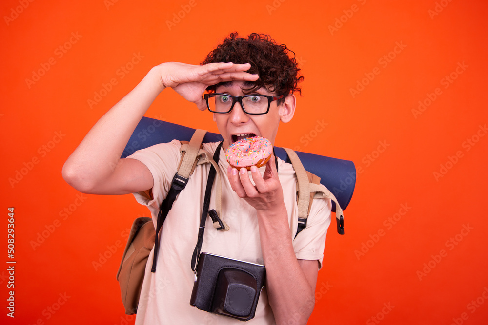 Young attractive tourist with a backpack. Orange background. Young attractive tourist with a backpack. Orange background.