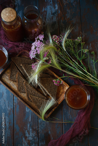 Traditional homemade beverage kvass in glasses and bottles with summer bouqute of rye and yarrow, flat lay. photo