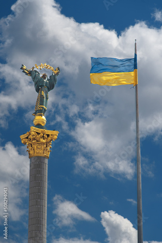 Obraz na płótnie Monument of Independence in Kiev and ukrainian flag against blue sky with white clouds. w salonie