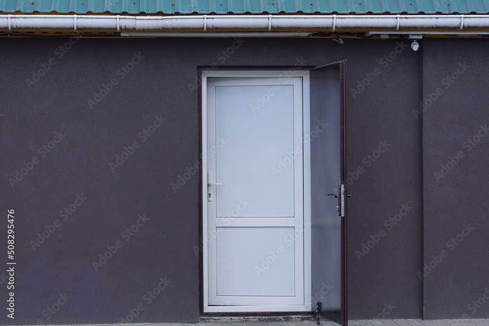 one white plastic door on a brown metal wall of a building on the street one white plastic door on a brown metal wall of a building on the street