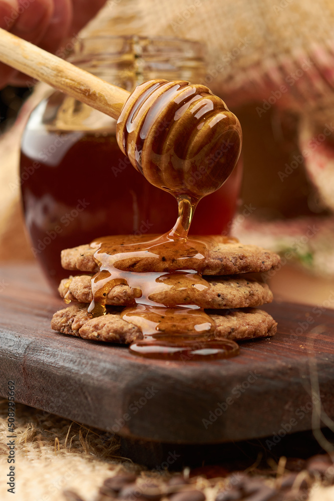 Homemade cookies made in an artisanal way, using a wooden server, honey is placed on a cutting board, in the background a jute bag made of natural fiber
