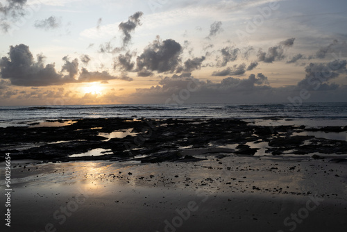 Reflection of sea water on the beach with low tide and exposed rocks