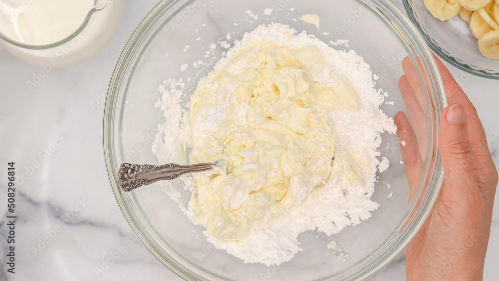 Cream cheese and powdered sugar mixing in a glass bowl, flat lay