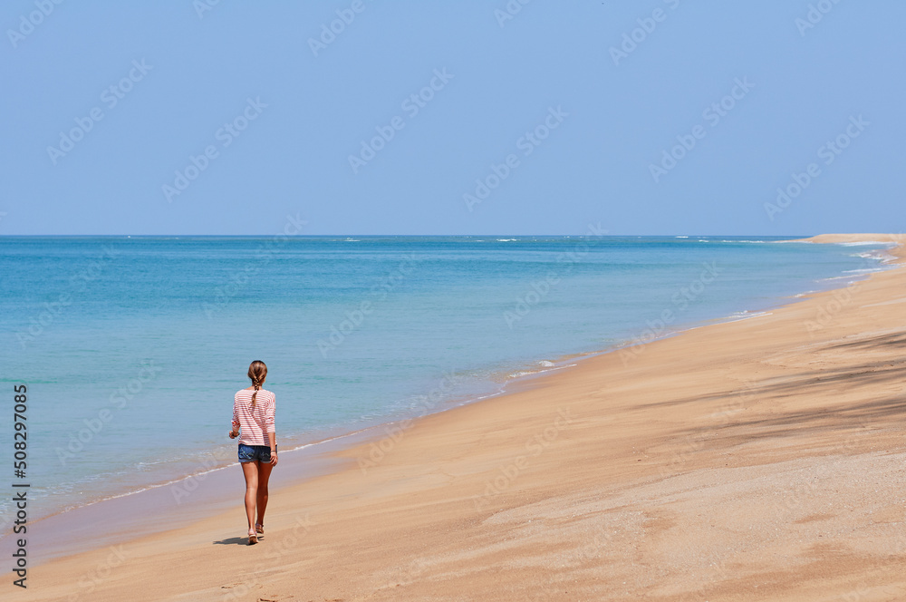Vacation on the shore. Young woman walking on tropical beach enjoying beautiful view. Vacation on the shore. Young woman walking on tropical beach enjoying beautiful view.