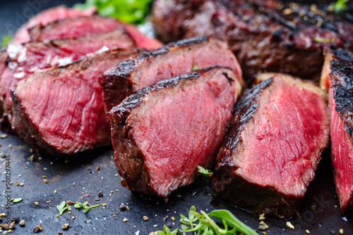 Barbecue dry aged wagyu roast beef steak with lettuce and spice served as close-up on a rustic black board photo