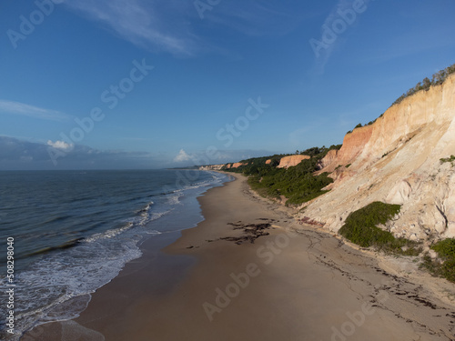Amazing land cliffs with the golden hour of the rising sun and beautiful beach in Parrancho, Arraial da Ajuda, Bahia, Brazil, South America. Aerial drone view.