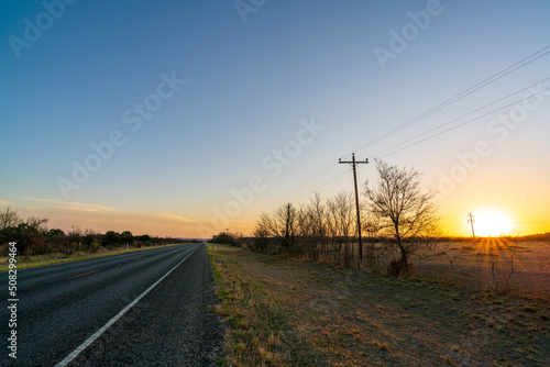 View of Two Lane Country Road in Texas With Sun Setting on the Right