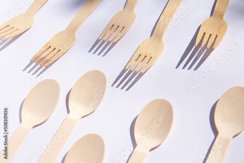 Wooden eco bamboo cutlery spoons and forks on bright white background. Meal time concept