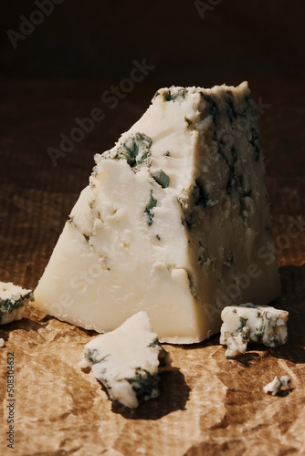 Blue cheese on a paper lining, close-up, selective focus on a piece of cheese
