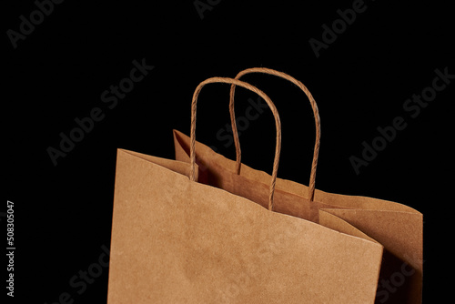Close-up of the twisted pens of a brown paper bag insulated on a black background.