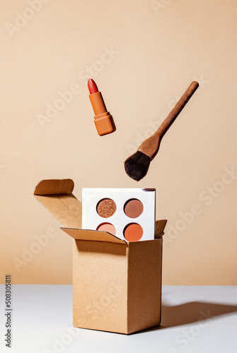 brown luxury lipstick and brush levitating over box and gainst a brown background photo