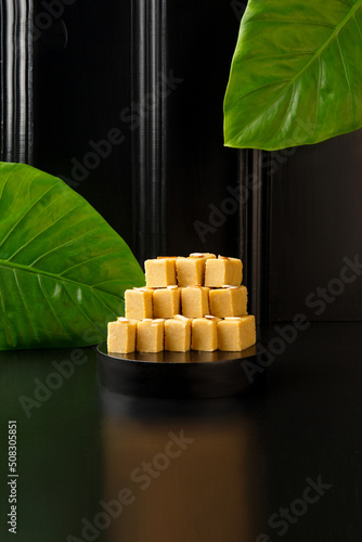 Special indian sweet badam barfi or mithai served in black tray isolated on dark background side view of pakistani dessert photo