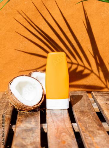coconut and a container of cream on a wooden table with a palm tree in the background