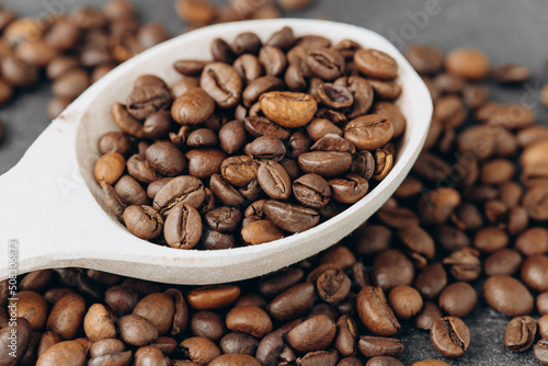 Coffee beans on wooden spoon isolated on dark background