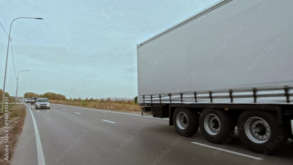 POV: was Overtaken by new Red truck with gray cargo trailer on high speed. International cargo delivering. Truck with goods in cargo trailer driving on multilane road. POV: was Overtaken by new Red truck with gray cargo trailer on high speed. International cargo delivering. Truck with goods in cargo trailer driving on multilane road.
