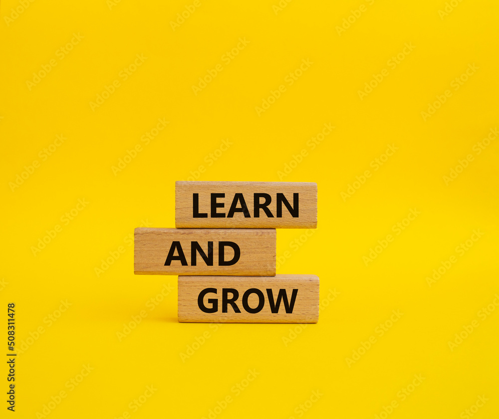 Learn and grow symbol. Concept words 'Learn and grow' on wooden blocks. Beautiful yellow background. Business and Learn and grow concept. Copy space. Learn and grow symbol. Concept words 'Learn and grow' on wooden blocks. Beautiful yellow background. Business and Learn and grow concept. Copy space.