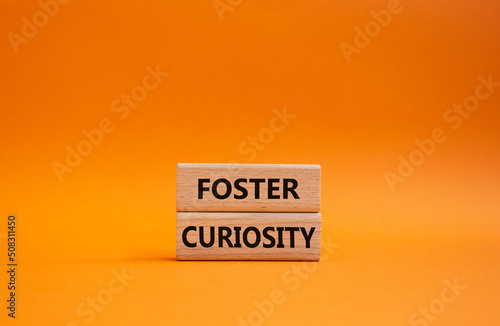 Foster curiosity symbol. Concept word Foster curiosity on wooden blocks. Beautiful orange background. Business and Foster curiosity concept. Copy space