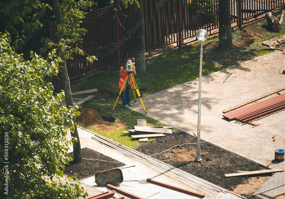 young engineer use the Total Station (tacheometer, theodolite) at urban landscaping design young engineer use the Total Station (tacheometer, theodolite) at urban landscaping design