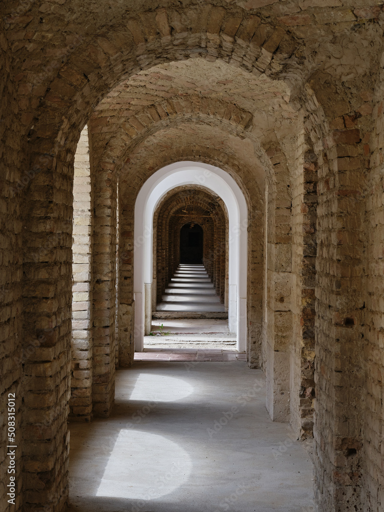 Arched brick corridor with shadows and daylight through the windows in the old fortress in Komárno, a place full of history, Slovakia