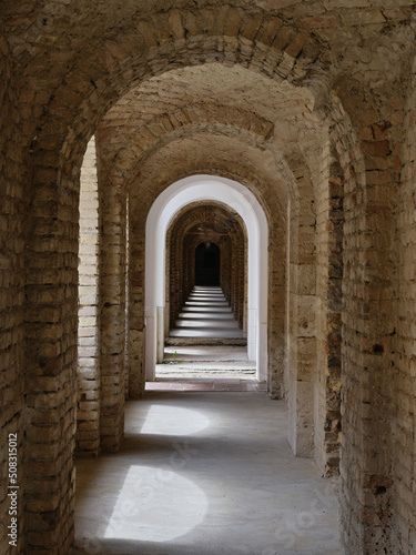 Arched brick corridor with shadows and daylight through the windows in the old fortress in Kom  rno  a place full of history  Slovakia