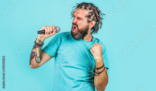 Karaoke. Bearded man singing in microphone. Emotional singer with braids. Sing a song in studio.