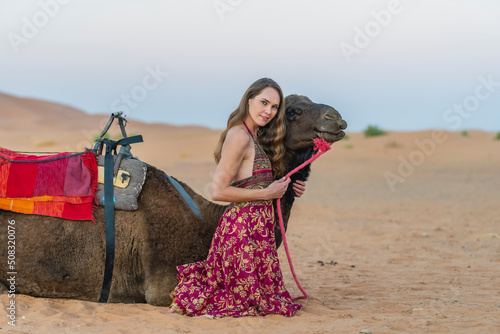 A Lovely Model Rides A Dromedary Camel Through The Saharan Desert On Their Camels In Morocco photo