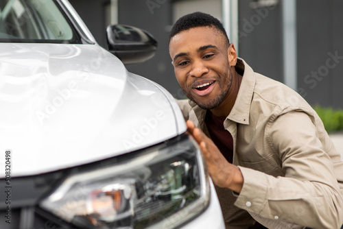 Happy afro man touching new auto, after buying in salon