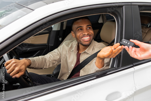 Test drive of a new car. Young black man grabs the car keys while sitting in the driver's seat