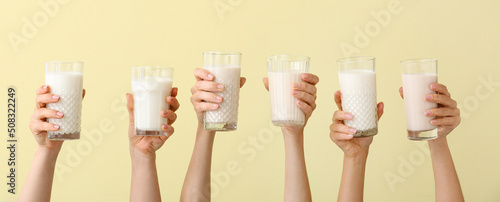 Cuadro en lienzo Female hands with glasses of vegan milk on yellow background