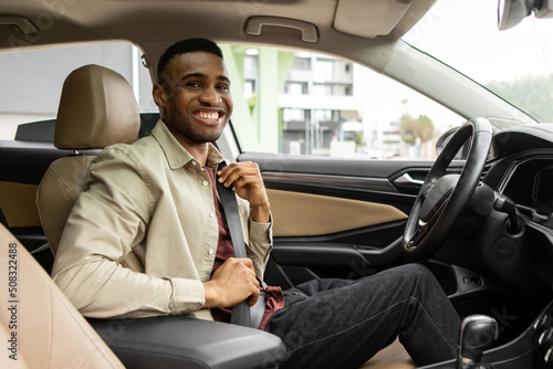 Portrait of an afro american man sitting in the driver's seat of a car and wearing a seat belt for safety © Home-stock