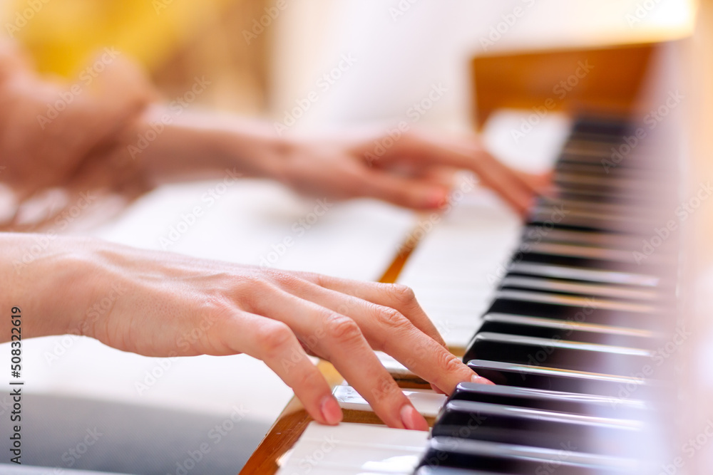 Fototapeta premium Close up of hands young talented woman playing the piano at home, performing classical music, getting ready to the classes in the music school. Musical artist create instrumental acoustic melody.