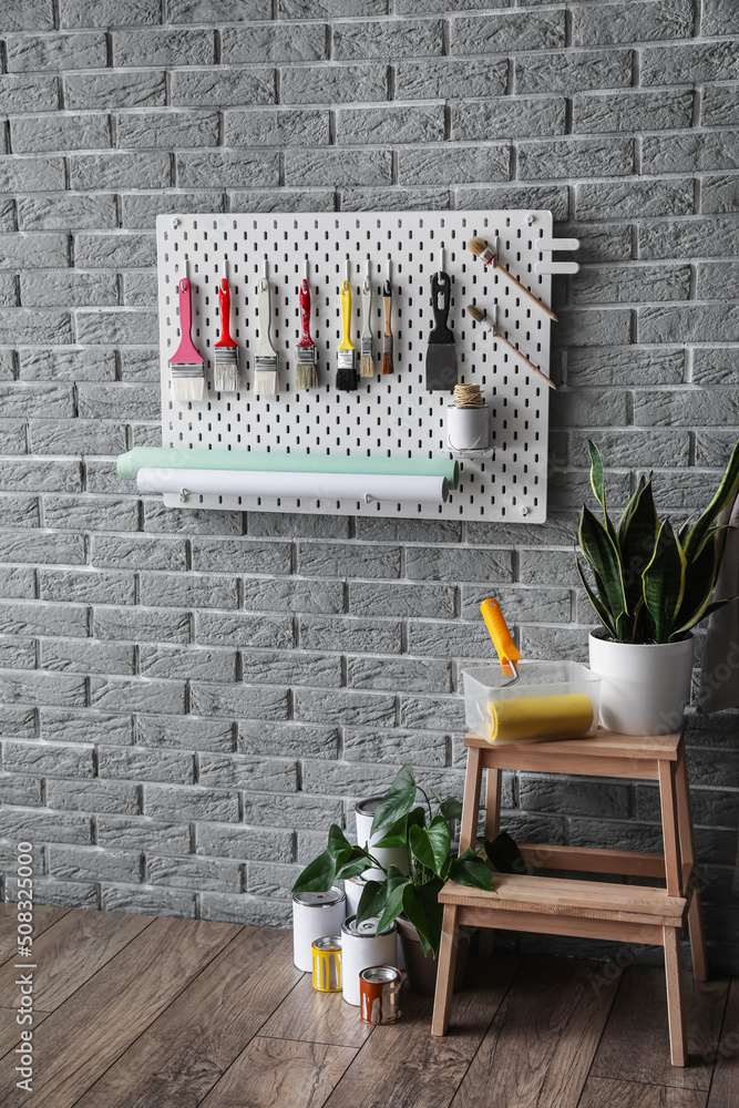 Stepladder stool with houseplant and pegboard with decorator's tools on