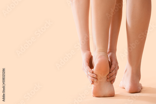 Фотография Young woman making foot massage on beige background, closeup