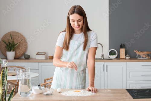 Young woman salting dough i...