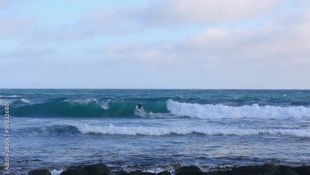 Surfer surfing waves on the beach on a sunny day at sunset surrounded by waves and cliffs in the nature - Great ocean road, Victoria, Australia. Surfer surfing waves on the beach on a sunny day at sunset surrounded by waves and cliffs in the nature - Great ocean road, Victoria, Australia.
