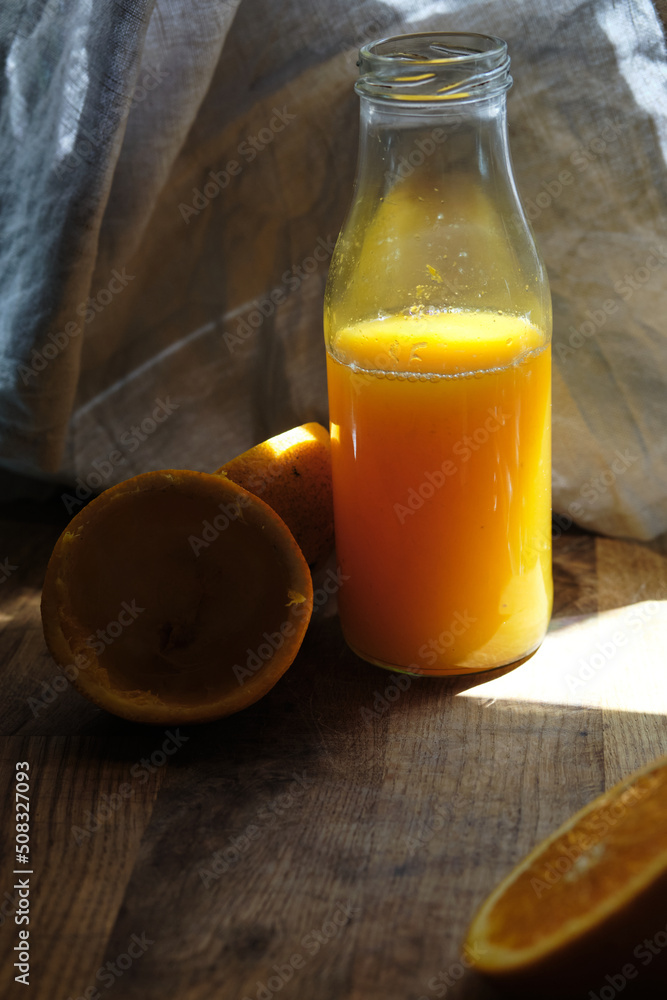Orange juice bottle on a wooden table with squeezed orange