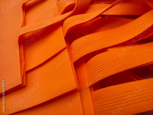 orange non-woven cloth tote bag. collections made of non-woven fabrics. pile of textured and porous polypropylene material. Partial view of the image photo