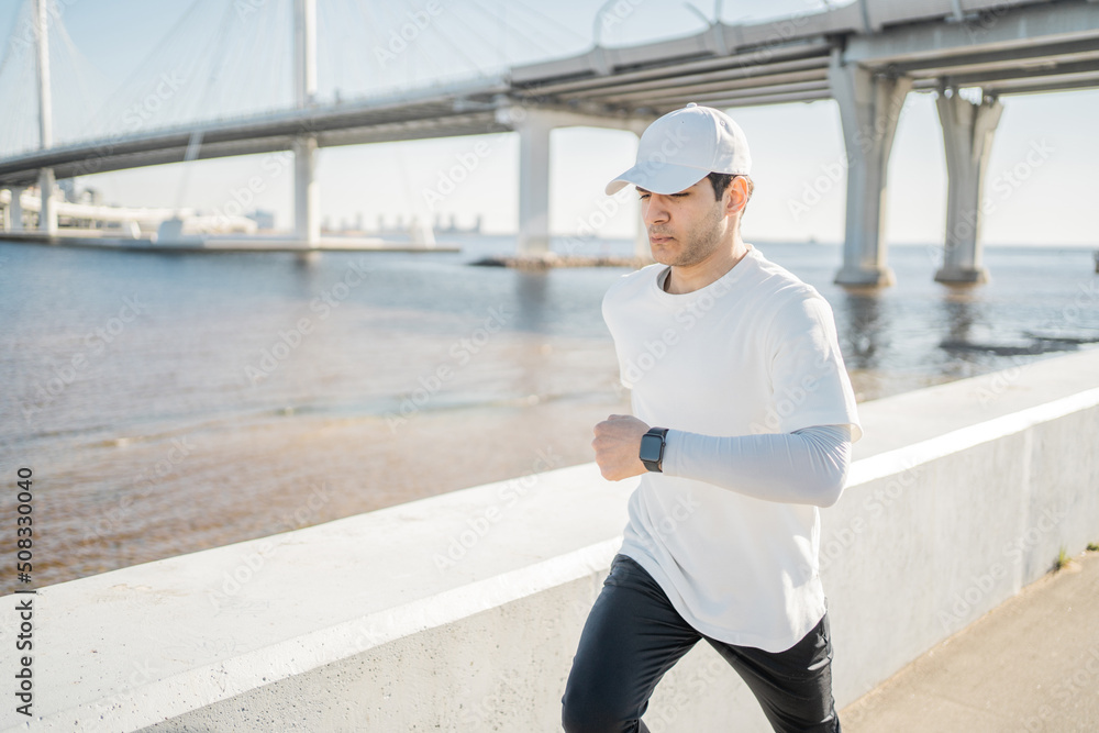 Athlete young man running outside active training, smart sports watch on hand