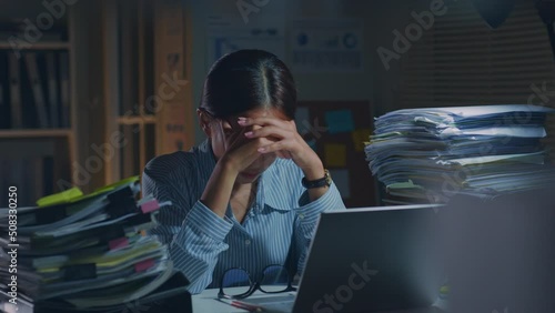 Young Asian office employee feeling tired, fatigue, exhausted while working overtime at night in office