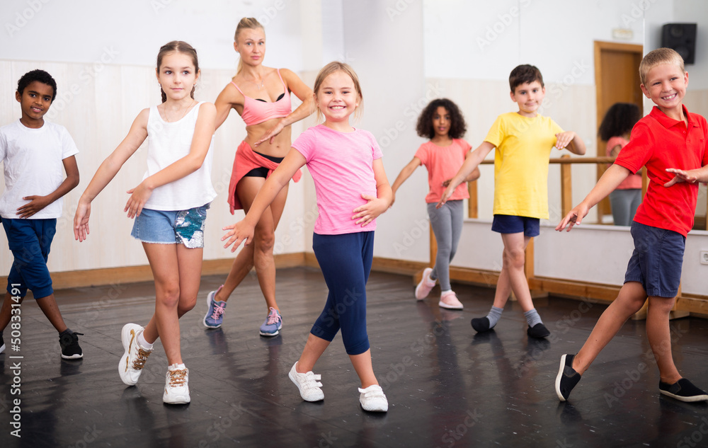 Obraz premium Smiling girls and boys doing dance workout during group class in fitness center