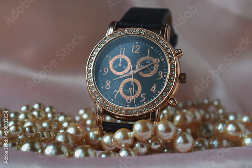 women's wristwatch with black strap on elegant pearl background