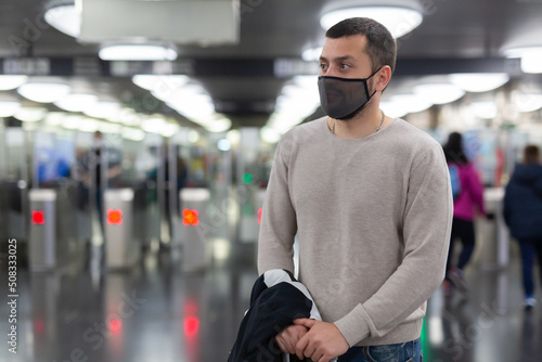Young man in protective face mask walking through underground station, waiting for train. Necessary precautions during coronavirus pandemic © JackF