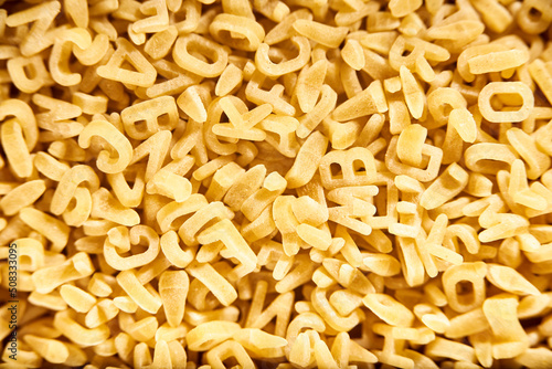 Uncooked alphabet soup pasta letters background. Food and education concepts.