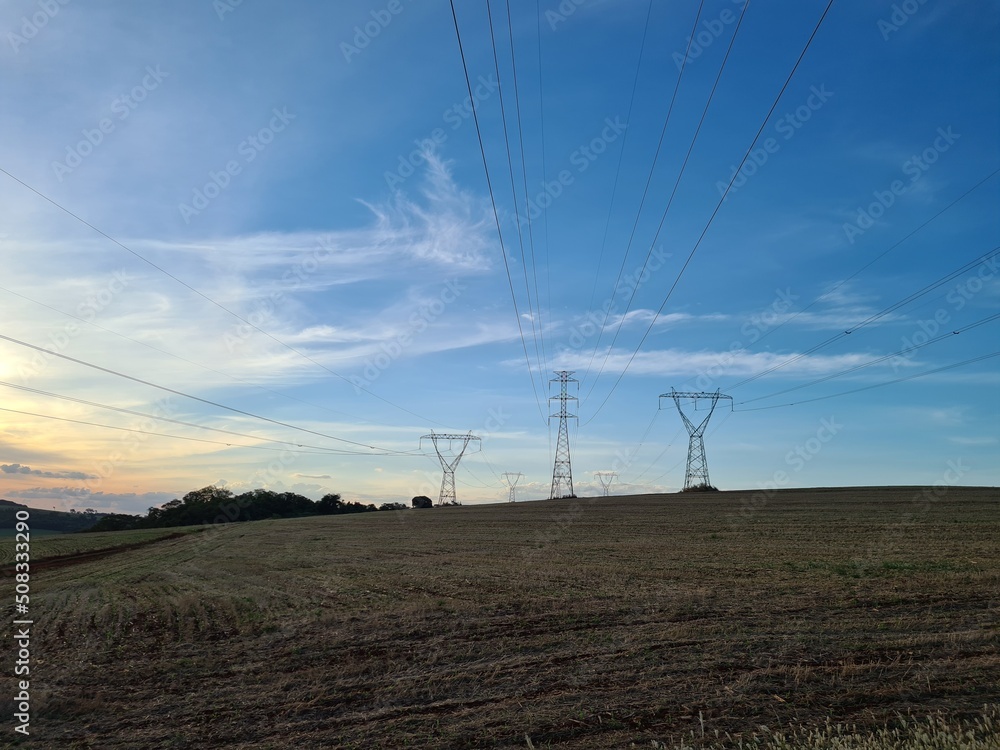 Electric power transmission towers in rural area during sunset.