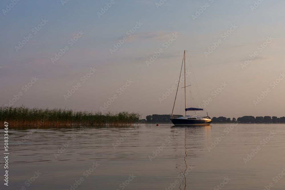 Sailing boat is illuminated by the sunset. Sunset on the lake.