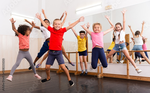 Group of cheerful children dancing and jumping in dance studio during class